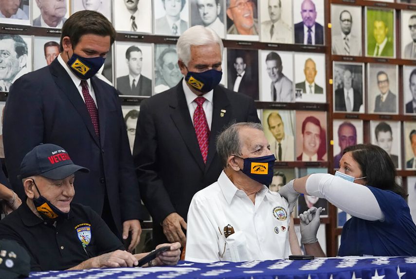 El gobernador de la Florida, Ron DeSantis, observa mientras aplican una dosis contra el COVID a un excombatiente de la Brigada 2506 en Miami.
