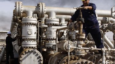 Dos hombres operan una estación de bombeo de petróleo.