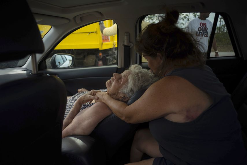Virginia Mosvold, de 84 años, se recuesta en el asiento del automóvil mientras su hija Sissel la consuela después de ser rescatadas de su hogar en Ol Freetown Farm, Bahamas.