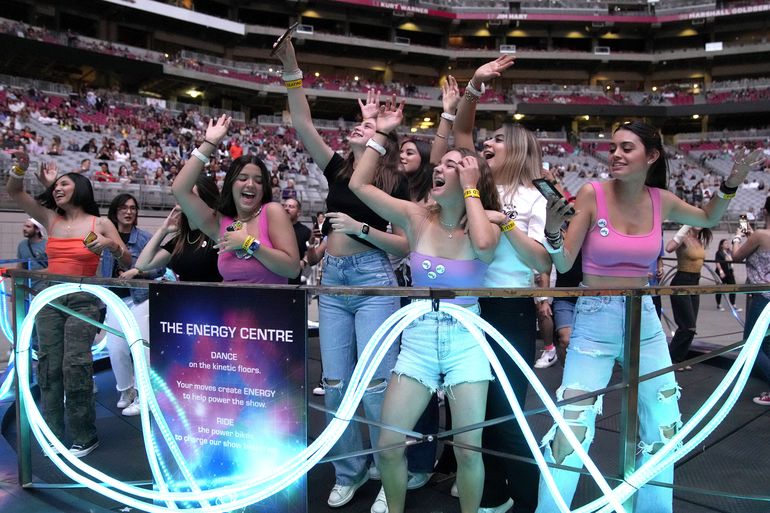 Asistentes bailan durante un concierto de la gira mundial Music of the Spheres de Coldplay el jueves 12 de mayo de 2022 en el State Farm Stadium en Glendale, Arizona.