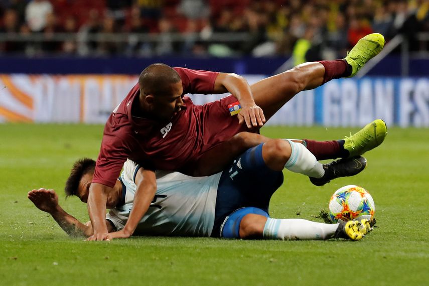 El delantero de la selección de Venezuela, José Rondón, cae ante la entrada del defensa de Argentina, Lisandro Martínez, durante el encuentro amistoso que disputaron esta noche en el estadio Wanda Metropolitano, en Madrid.