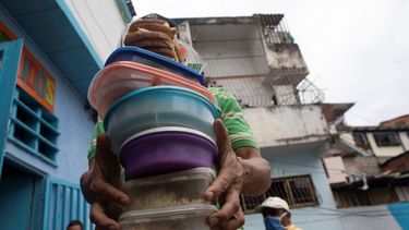 Un voluntario carga comida a ser repartida en un comedor popular en el barrio caraqueño de Petare.