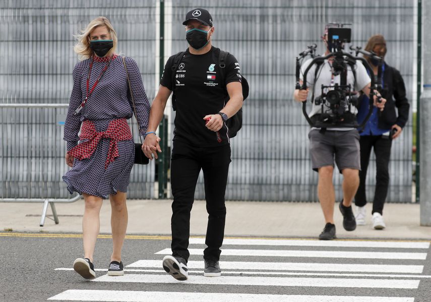 El piloto de F&oacute;rmula 1 de la escuder&iacute;a Mercedes Valtteri Bottas (derecha) y su novia Tiffany Cromwell llegan al paddock para el Gran Premio del 70mo aniversario en el circuito de Silverstone en Inglaterra, el jueves 6 de agosto de 2020.&nbsp;
