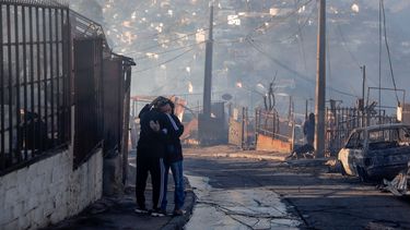 Personas abrazadas en los escombros de casas destruidas por un incendio forestal en los cerros de Viña del Mar, en la región de Valparaíso, Chile, el 23 de diciembre de 2022. Al menos dos personas murieron y unas 400 casas fueron dañadas o destruidas en un incendio que estalló el jueves en el balneario chileno de Viña del Mar, lo que llevó al gobierno a declarar el estado de emergencia.