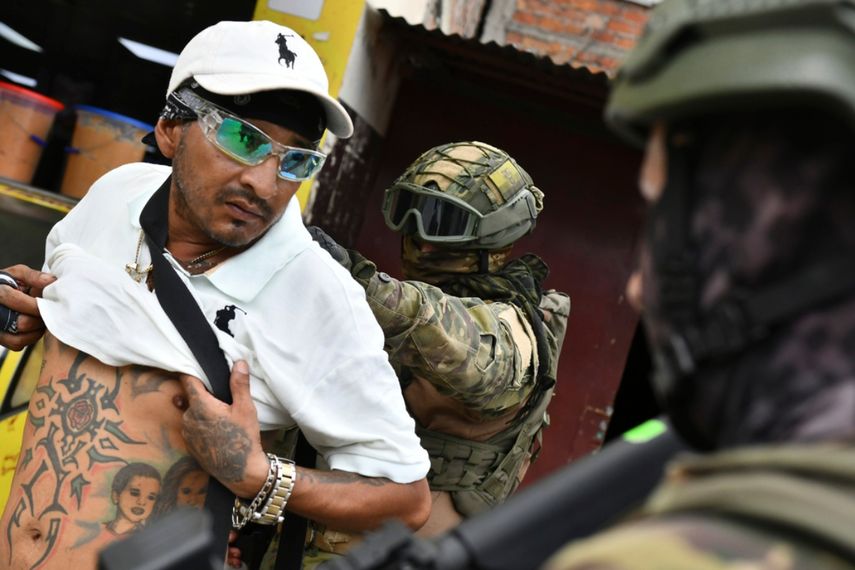 Un militar revisa la espalda de un hombre, comprobando sus tatuajes, en un control en Portoviejo, Ecuador.