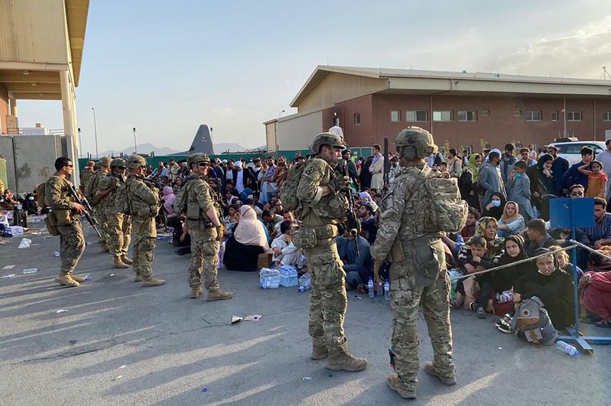 Soldados estadounidenses montan guardia mientras los afganos esperan abordar un avión militar estadounidense para salir de Afganistán, en el aeropuerto militar de Kabul el 19 de agosto de 2021 después de la toma militar de Afganistán por los talibanes.