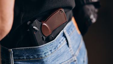 Un hombre porta un arma entre su pantalón.