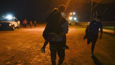 Un migrante carga a un niño en un área de admisión después de entregarse al cruzar la frontera entre Estados Unidos y México, en La Joya, Texas.&nbsp; 