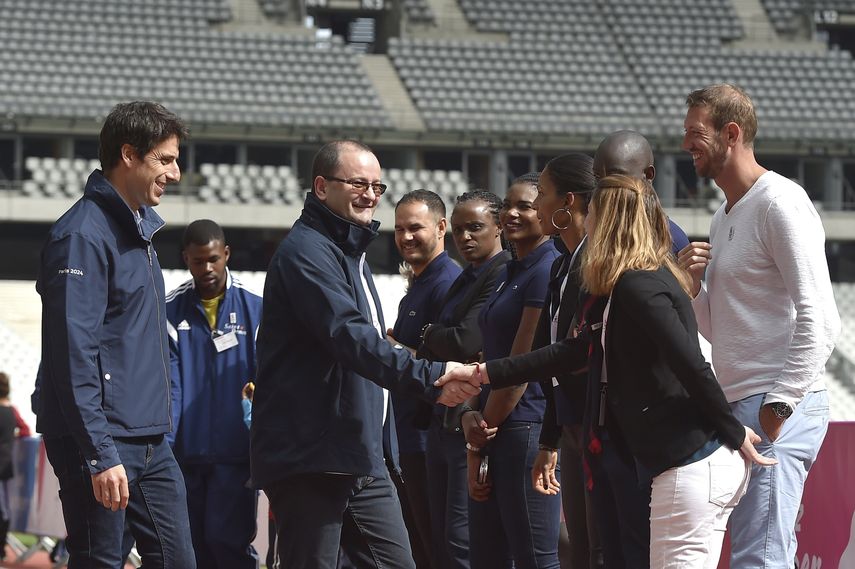 El presidente de la Comisión de Evaluación del Comité Olímpico Internacional (COI), Patrick Baumann (centro), y el co-presidente de la candidatura de París Tony Estanguet (izquierda) saludan a atletas durante su visita al Estadio de Francia en Saint Denis.
