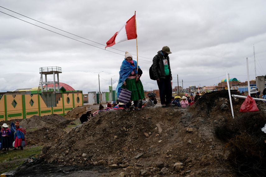 &nbsp;Una mujer aymara con una bandera peruana se para sobre un montículo de tierra que sirve de barricada en un camino instalada por manifestantes contra el gobierno en Acora, sur de Perú, 29 de enero de 2023.
