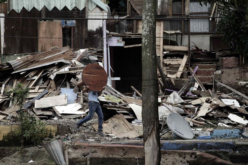 Un hombre carga un tablón de madera en medio de los escombros dejados por el azote del huracán Nate el viernes 6 de octubre de 2017, en la localidad del Barrio Los Anonos, en el cantón de Escazú, al oeste de San José, Costa Rica.   