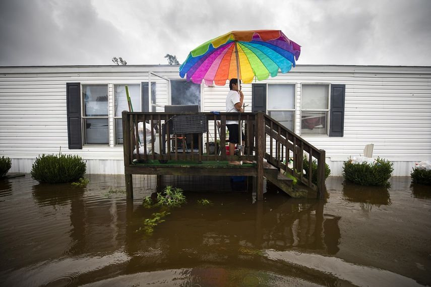 Erick Martínez cocina pollo en un parrillera mientras su casa permanece rodeada de agua en una zona de Carolina del Norte.&nbsp;