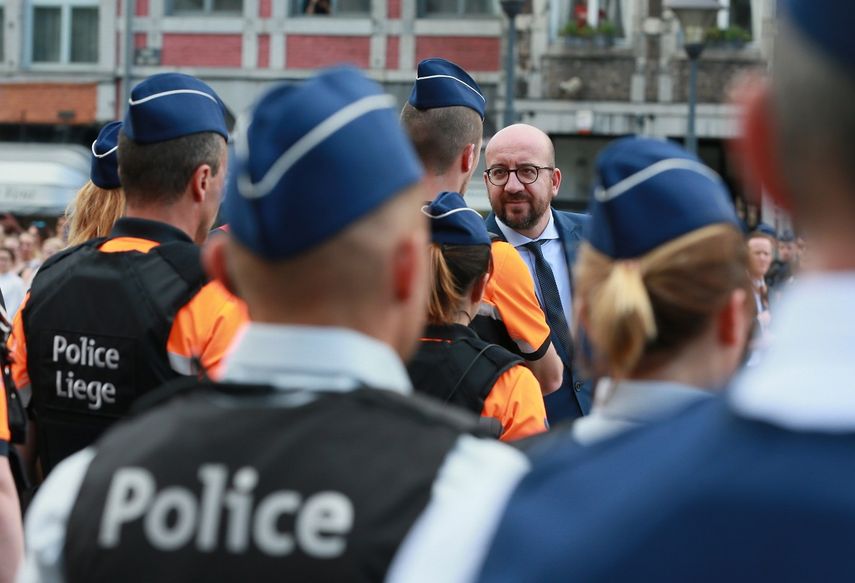 El primer ministro de Bélgica, Charles Michel (cen.), saluda a agentes de policía de la ciudad de Lieja durante un homnaje por las víctimas del ataque terrorista de este martes ante el Café Les Augustins, en esa ciudad belga.