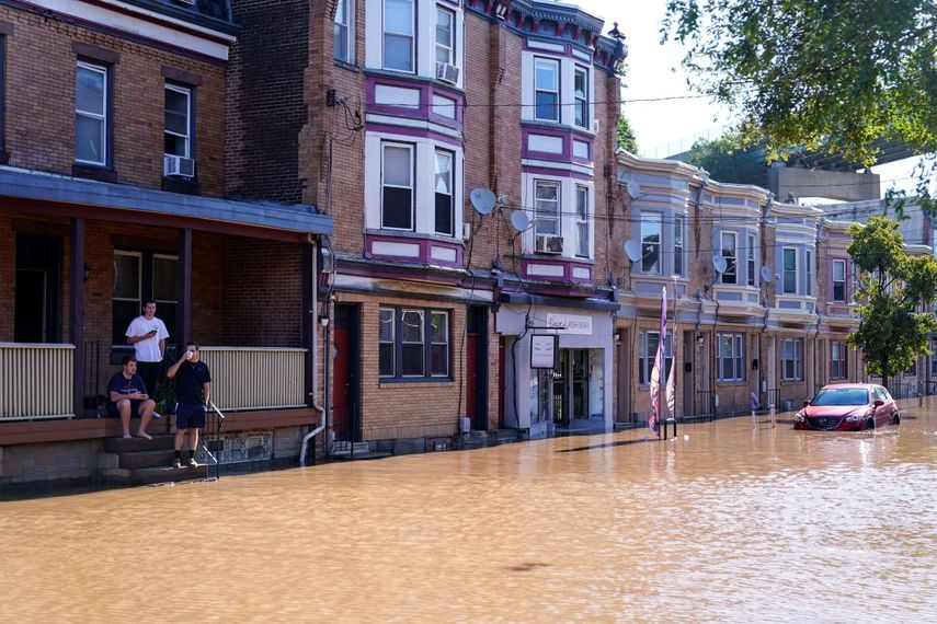 Tres personas miran una calle inundada tras el desbordamiento del río Schuylkill, el jueves 2 de septiembre de 2021, en el sector East Falls de Filadelfia.&nbsp;