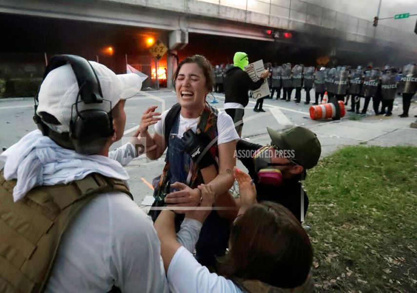 Los manifestantes ayudan a una mujer que recibió un disparo en la garganta con una bala de goma durante las protestas que se tornaron violentas en la ciudad de Miami, el sábado 30 de mayo de 2020.
