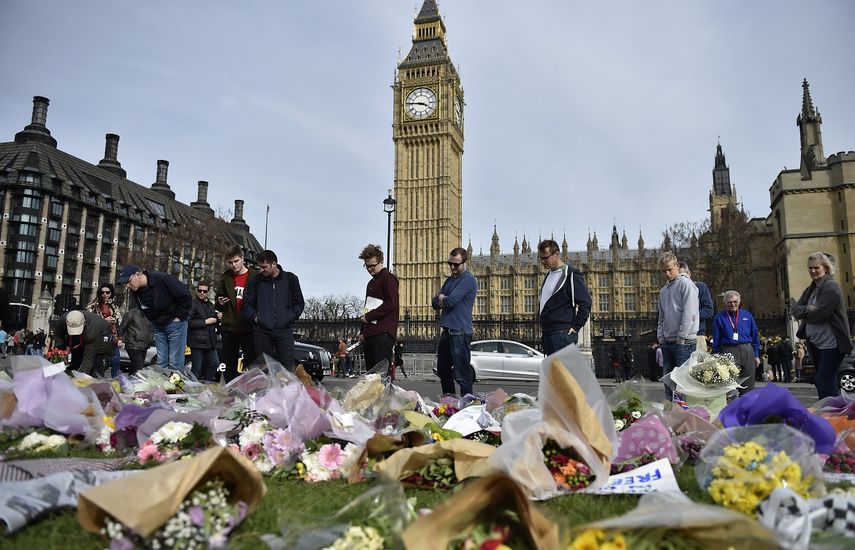 Paseantes miran las flores depositadas cerca del lugar donde ocurrió el atentado el pasado 22 de marzo.