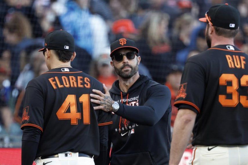 El venezolano Wilmer Flores, de los Gigantes de San Francisco, es felicitado por el mánager Gabe Kepler, tras el triunfo sobre los Rojos de Cincinnati, el sábado 25 de junio de 2022.
