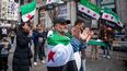 Varias personas sujetan banderas durante una concentración por el 12º aniversario de la Revolución Siria, en la plaza de Callao, a 18 de marzo de 2023, en Madrid (España).&nbsp;