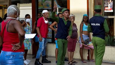 Agentes de polic&iacute;a vigilan las filas de espera para comprar alimentos.