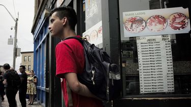 En esta fotografía del domingo 30 de junio de 2019 unas personas se preparan para abordar un autobús frente a un restaurante latino en Chelsea, Massachusetts.