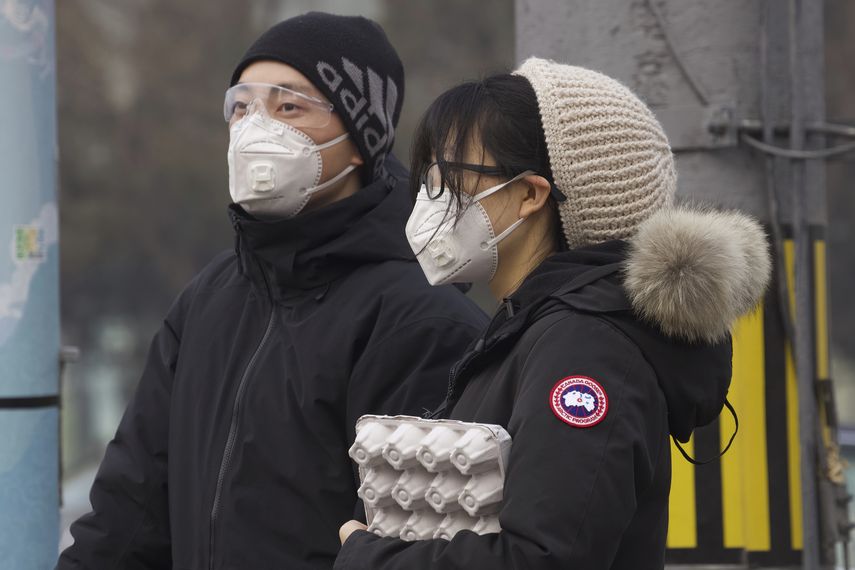 Residentes se protegen con una mascarilla facial mientras esperan en un sem&aacute;foro en Beijing, China, el 13 de febrero de 2020.&nbsp;
