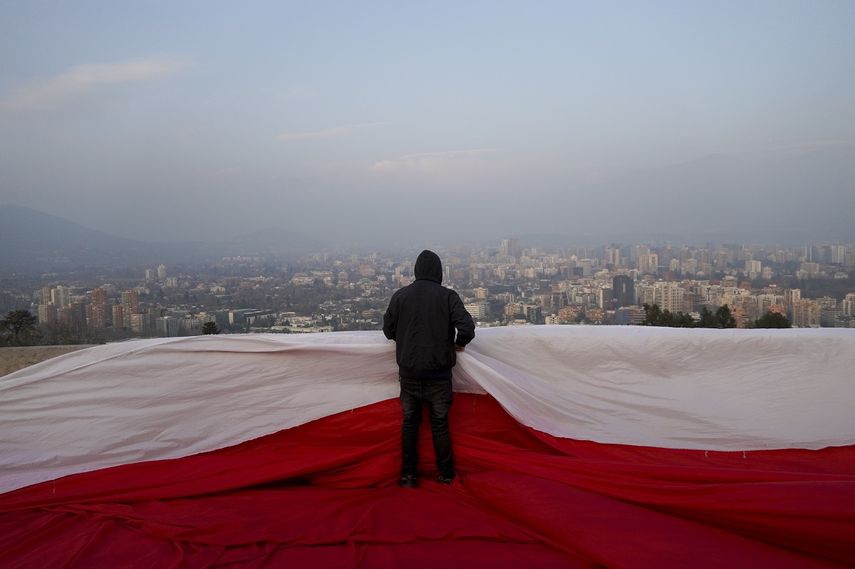 Manifestantes chilenos se colocaron, sobre una bandera gigante antes de una manifestación en contra de la nueva Constitución propuesta para el país, en Santiago, Chile, el 1 de septiembre de 2022.&nbsp;