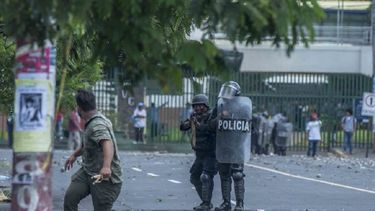 Un oficial de la Policía del régimen de Daniel Ortega apunta con su arma a un manifestante.