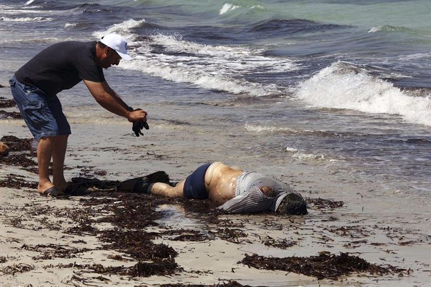 Un miembro de la Media Luna Roja comprueba el estado del cuerpo sin vida de un inmigrante en la costa de Zauara, en Libia. (EFE)