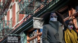 Dos mujeres con mascarillas para protegerse del COVID-19 caminan por el distrito SoHo en Nueva York.
