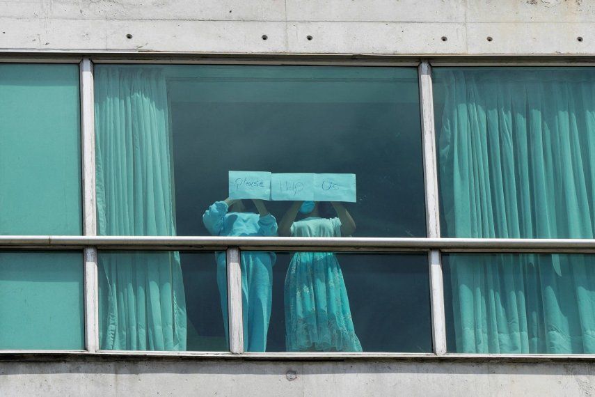 Migrantes deportados de EE UU colocan papeles con un mensaje escrito en la ventana del Hotel Decápolis donde se encuentran alojados temporalmente en Ciudad de Panamá, 18 de febrero de 2025