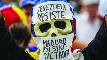 Un manifestante que porta una máscara en alusión al dictador.