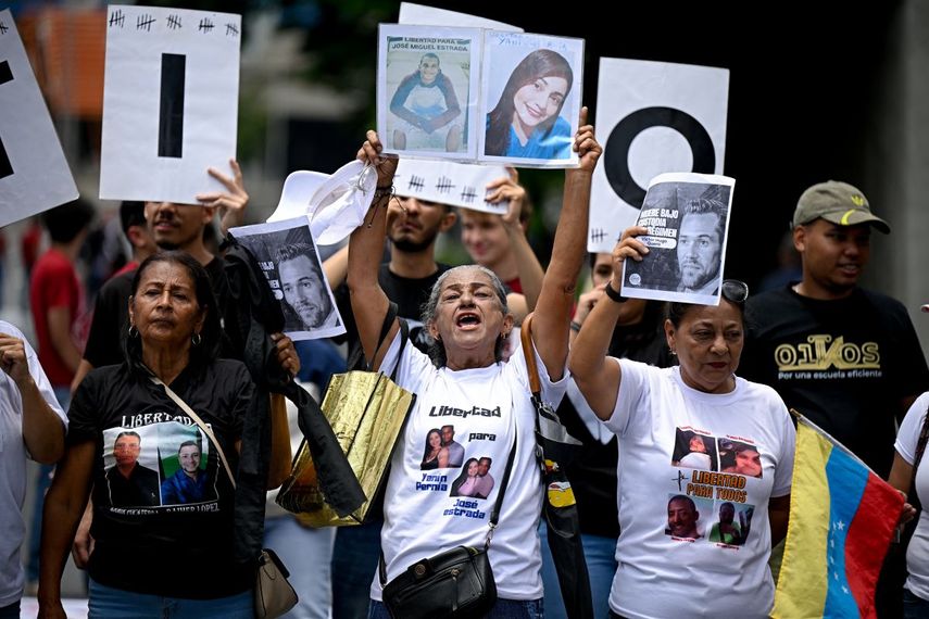 Estudiantes y familiares de presos políticos exhiben retratos de los reclusos durante una protesta para exigir su liberación frente a la Universidad Central de Venezuela (UCV) en Caracas, el 13 de mayo de 2026. Estudiantes universitarios y sus familias bloquearon la principal avenida de Caracas ese día para protestar por la desaparición forzada de unos 50 presos políticos en Venezuela y la muerte bajo custodia de aproximadamente 20 detenidos en la última década.