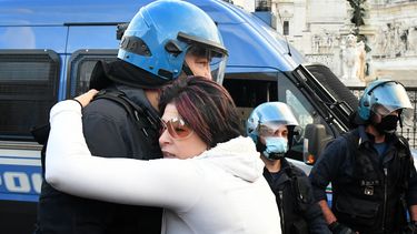 Un manifestante abraza a un oficial de policía en provocación el 15 de noviembre de 2020, en Roma, durante una manifestación antimáscaras y contra las restricciones del gobierno sobre la pandemia Covid-19.