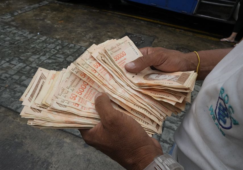 En esta imagen de archivo, tomada el 5 de agosto de 2021, un hombre cuenta billetes por el equivalente a un dólar en una parada de autobús en Caracas, Venezuela.&nbsp;