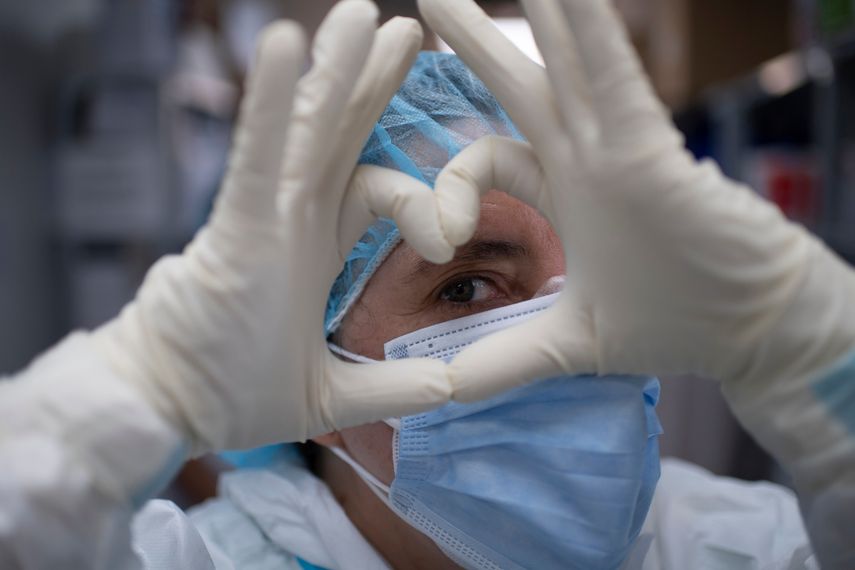Una trabajadora de salud espa&ntilde;ola y voluntaria de la Fundaci&oacute;n SAMU forma la figura de un coraz&oacute;n con sus manos antes de ingresar a la unidad de cuidados intensivos del Hospital El Salvador para atender a los pacientes afectados por el nuevo coronavirus, COVID-19, en San Salvador, el 12 de agosto. 2020.