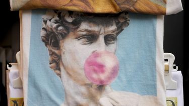 Una bolsa con un estampado de la estatua de David de Miguel Ángel del siglo XVI con una bomba de chicle a la venta, entre otros recuerdos, en una tienda en el centro de Florencia, centro de Italia, el lunes 18 de marzo de 2024.