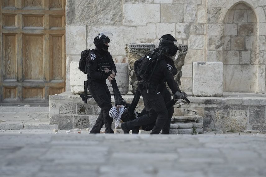 Efectivos de la policía israelí trasladan a un manifestante palestino durante enfrentamientos en el complejo de la mezquita de Al Aqsa, en la Ciudad Vieja de Jerusalén, el 22 de abril de 2022.&nbsp;