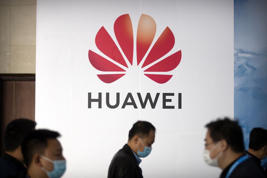 Varias personas pasan frente al logo de la compañía de tecnología Huawei.