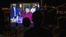Gente mira la juramentación del presidente Daniel Ortega para un cuarto período consecutivo en una pantalla jugante en un barrio de Managua, Nicaragua, 10 de enero de 2022. 