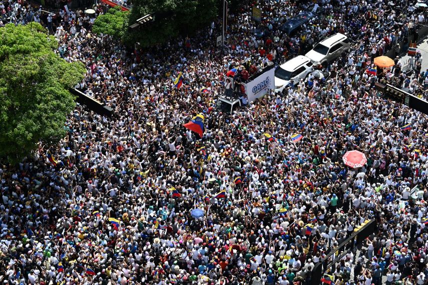 La líder de la oposición venezolana María Corina Machado (centro), ondea una bandera nacional encima de un camión durante una protesta convocada por la oposición para que se reconozca la 