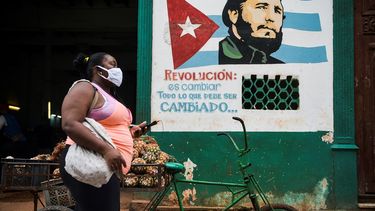 Una mujer con mascarilla camina cerca de un cartel que representa al fallecido líder cubano Fidel Castro en el que se lee “La revolución está cambiando todo lo que hay que cambiar” en La Habana, el 21 de enero de 2021. 