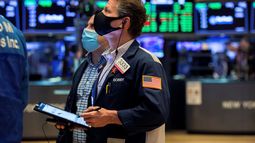 Agentes de la Bolsa de Nueva York miran una pantalla en el piso de remate.