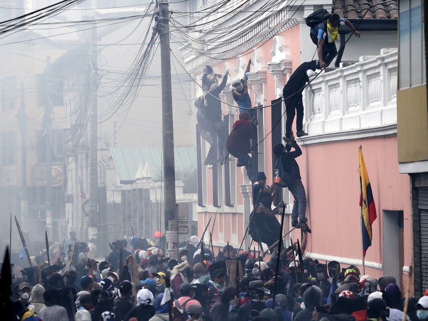 Manifestantes antigubernamentales escalan la fachada de una vivienda para llegar a la azotea, buscando un lugar desde donde tener ventaja en su enfrentamiento con la polic&iacute;a, en Quito, Ecuador. Las protestas, que comenzaron tras la decisi&oacute;n del presidente del pa&iacute;s, Len&iacute;n Moreno, de recortar los subsidios, lo que provoc&oacute; un alza en el precio de los combustibles, duraron varios d&iacute;as. Imagen tomada el 11 de octubre de 2019.