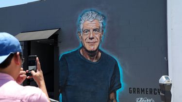 Un hombre toma una foto de un mural con la imagen de Anthony Bourdain en una pared del restaurante Gramercy, en Santa Mónica.