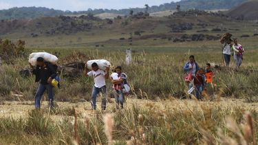Un grupo de&nbsp;venezolanos camina hacia Brasil a través de un campo, en Pacaraima, estado de Roraima, Brasil, el viernes 22 de febrero de 2019.