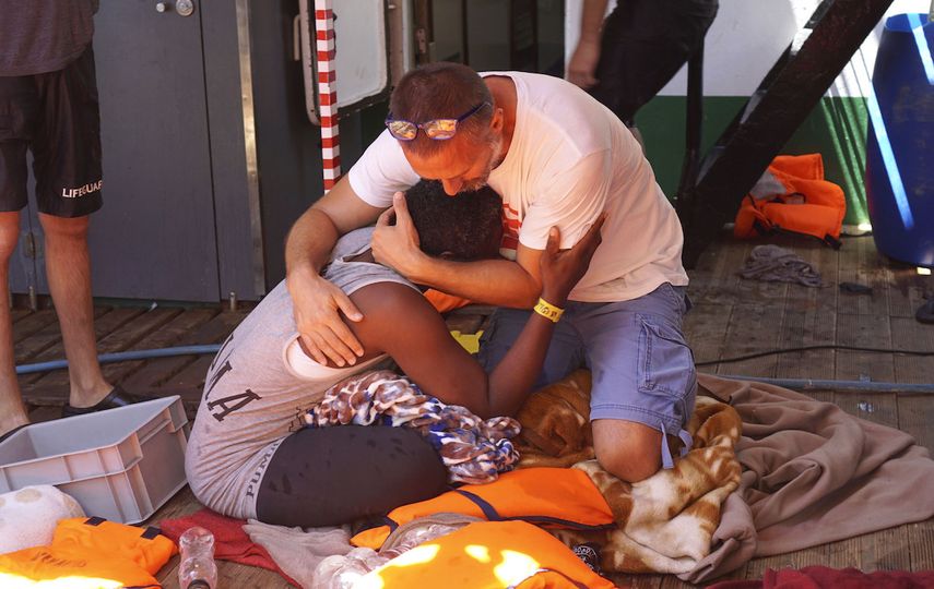 Un inmigrante es consolado por un tripulante del barco español humanitario Open Arms frente a la costa de la isla siciliana de Lampedusa, en el sur de Italia, el domingo 18 de agosto de 2019.&nbsp;&nbsp;