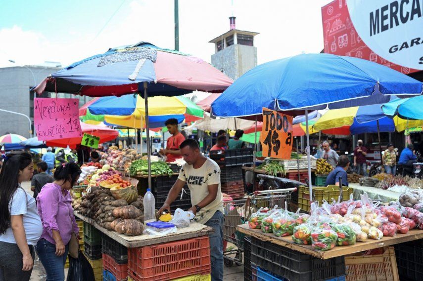 Una mujer compra comestibles, los carteles anuncian los precios en dólares en el mercado Quinta Crespo en Caracas el 20 de diciembre de 2022.