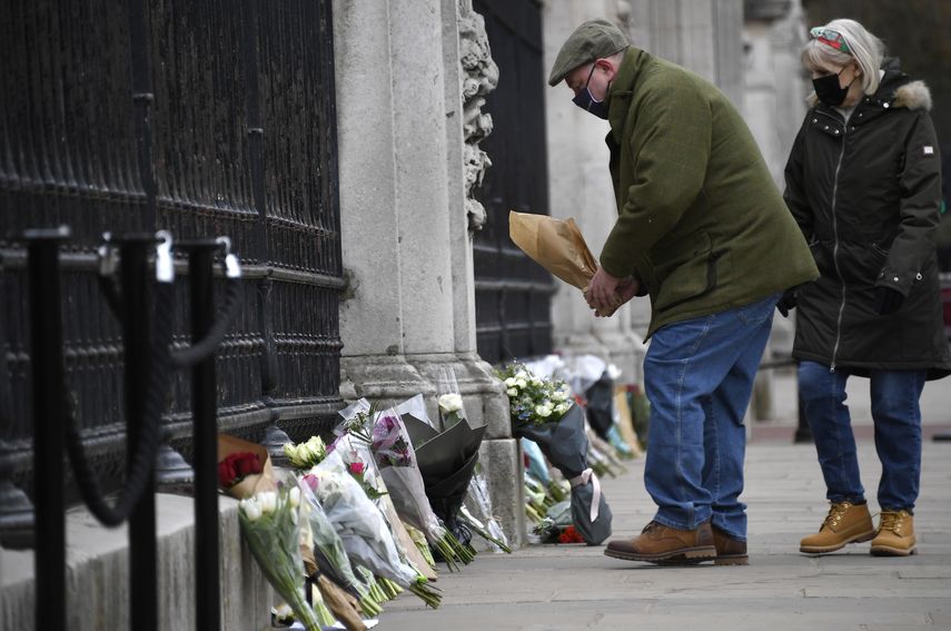 Un hombre deja un ramo de flores en la puerta del Palacio de Buckingham, en Londres, el 10 de abril de 2021, un día después de la muerte del príncipe Felipe, el marido de la reina Isabel II.&nbsp;