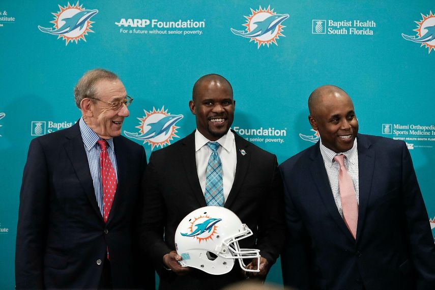 El dueño de los Dolphins, Stephen Ross, izquierda, el entrenador en jefe de Miami, Brian Flores, centro, y el gerente general Chris Grier, derecha, posan previo a una conferencia de prensa el 4 de febrero de 2019, en Davie, Fla. Flores fue despedido al final de la temporada 2021 y ahora está demandando al NFL y a tres equipos por presuntas prácticas racistas en el proceso de contratación de entrenadores y gerentes generales.