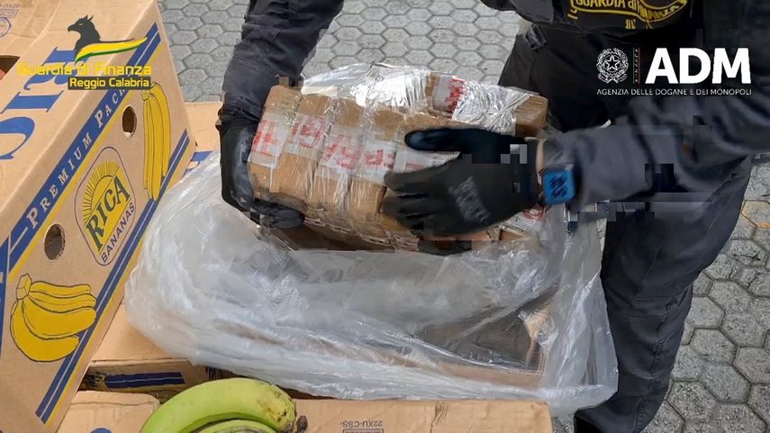 En esta imagen tomada de un video proporcionado por la policía italiana de finanzas, un agente sostiene bolsas de cocaína luego de ser encontradas escondidas en un contenedor cargado de bananas, el martes 16 de mayo de 2023 en el puerto de Gioia Tauro, en el sur de Italia.